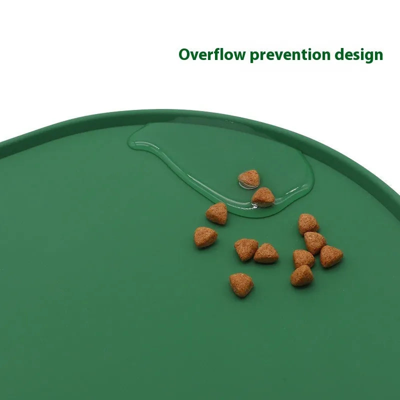 Green silicone cat feeding placemat with food and water bowls on it, on a wooden floor.