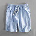 Man wearing black and white striped casual cotton shorts with a loose straight leg fit.