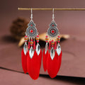 Close-up of a pair of bohemian feather and leaf pattern drop earrings in a light pink electroplated finish.