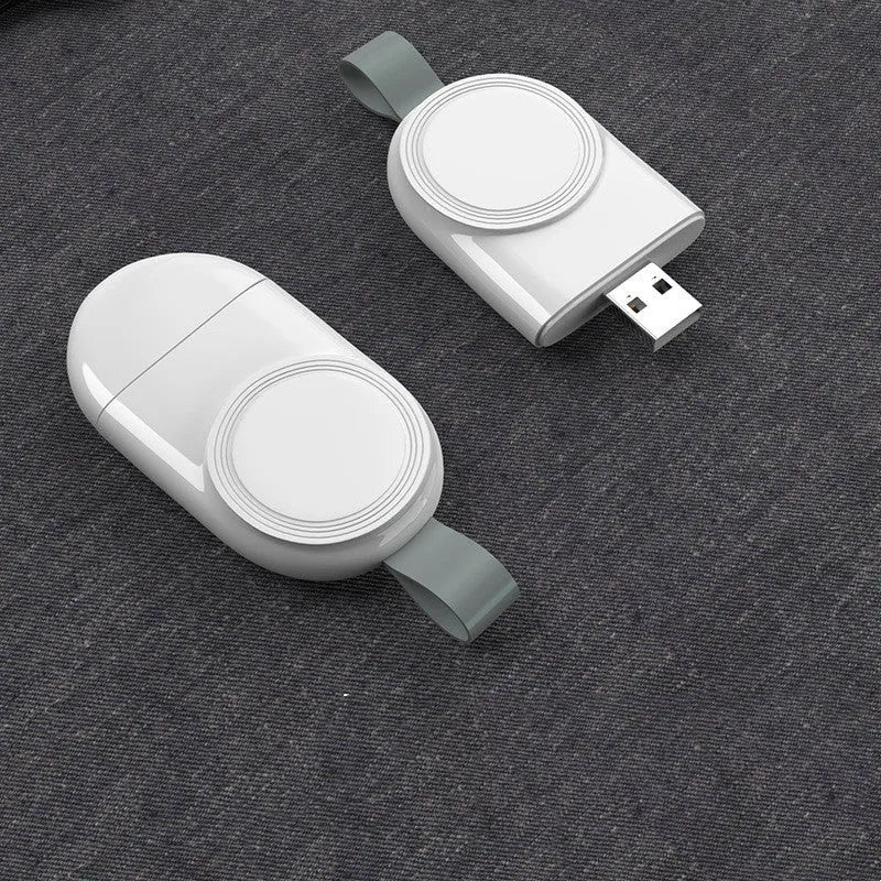 Portable Apple Watch wireless charging dock in white on a wooden table, with USB cable attached.