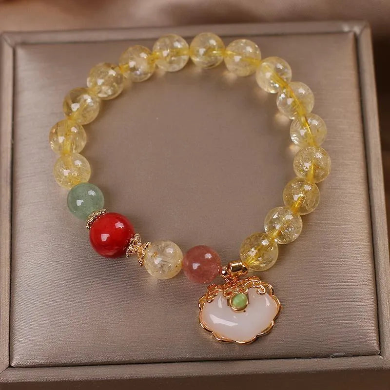 Close-up of a women's adjustable bracelet with a yellow citrine jade ruyi pendant on an alloy chain.