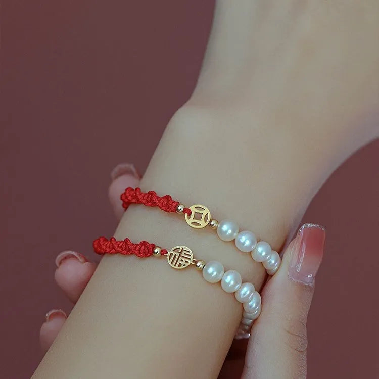 Women's pearl braided red rope bracelet with 14K gold plated fu character charm in geometric shape on white background