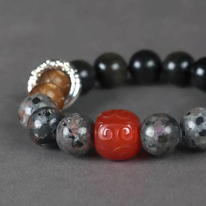 Gold obsidian flame stone and red agate unisex bracelet on a neutral background