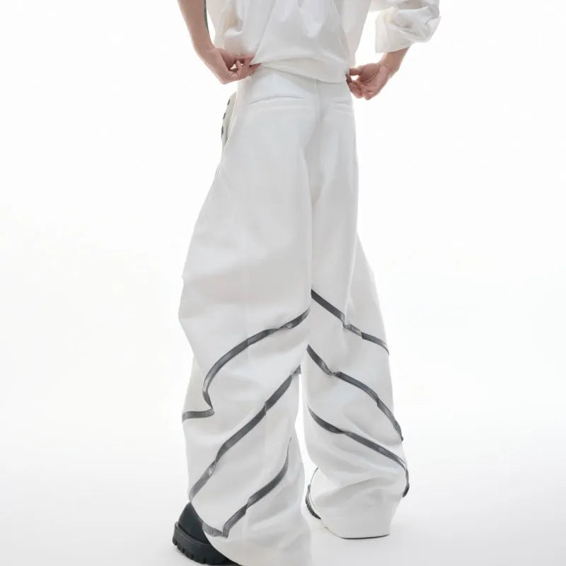 Men's black trousers with metal striped rivet details, pleated front, and a structured three-dimensional cut.