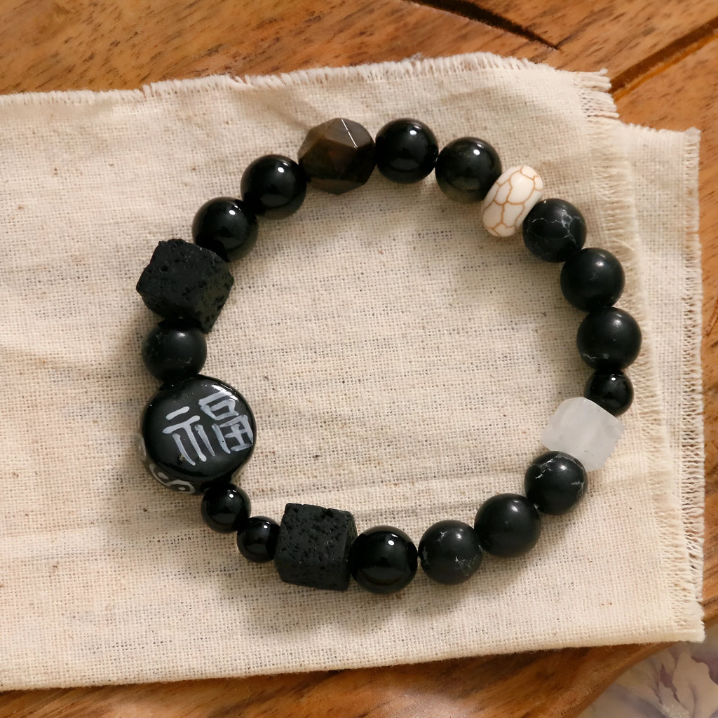 Natural black agate and ceramic round bead hand-woven bracelet on plain background, unisex original design