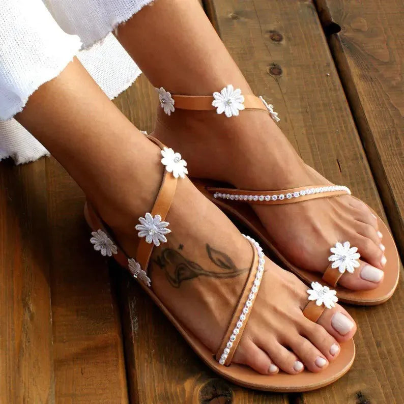Brown women's beach sandals with floral pattern, flat rubber sole, and herringbone toe design