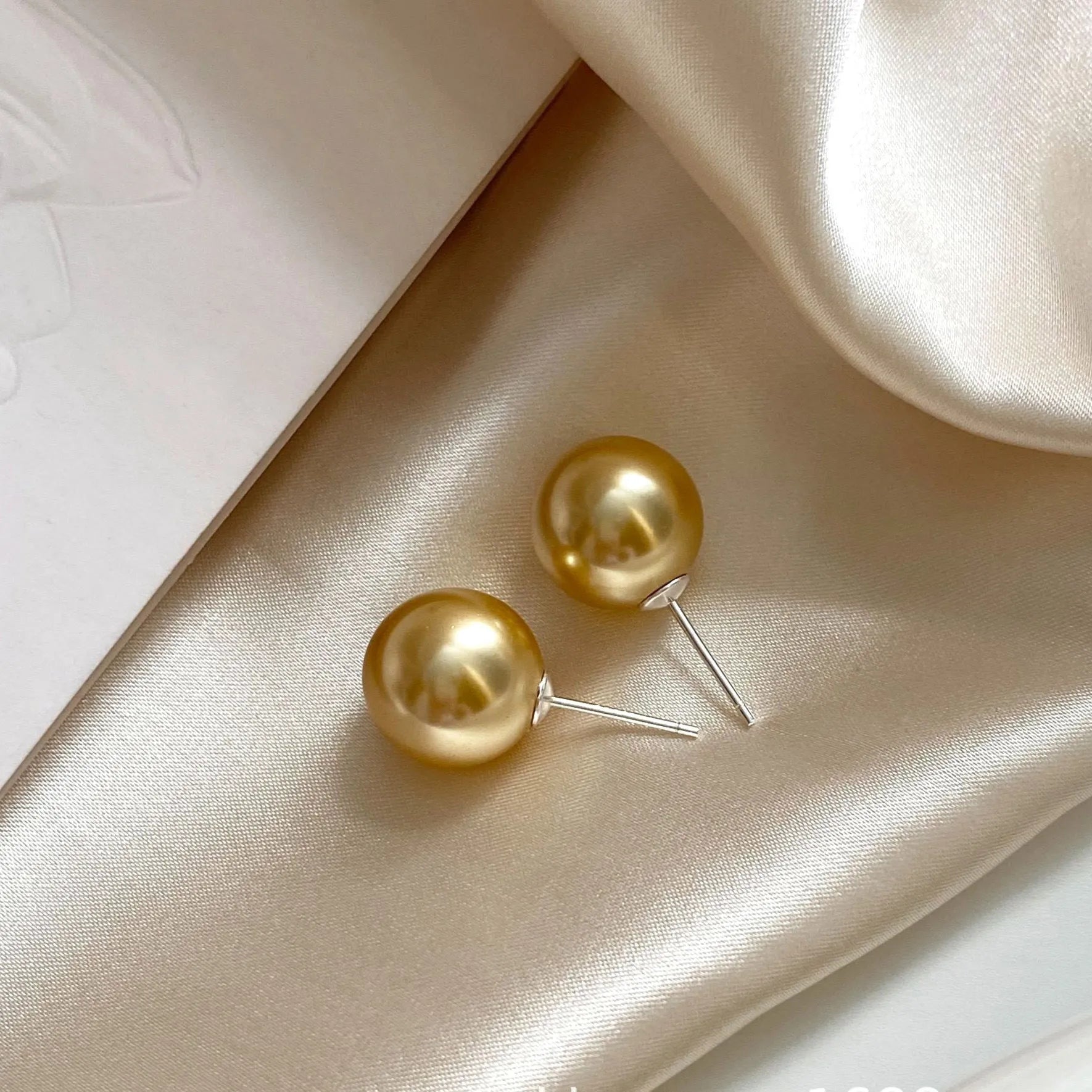 Geometric large pearl stud earrings with eight-point star design in silver setting.