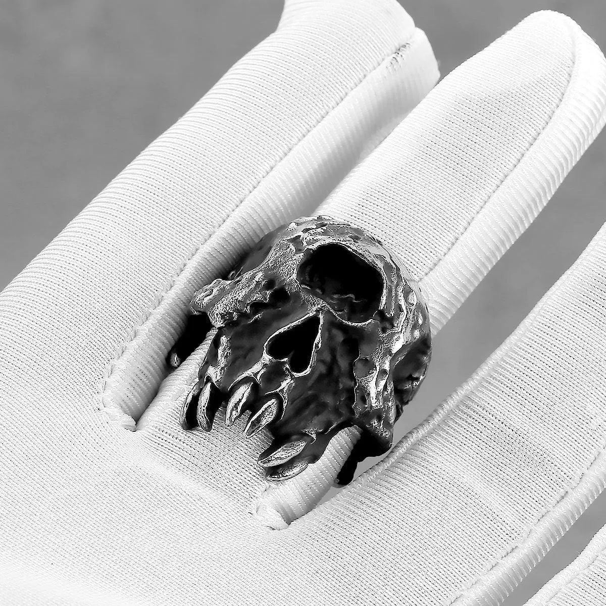 Close-up of a silver-toned alloy ring featuring a detailed one-eyed skull design on a finger.