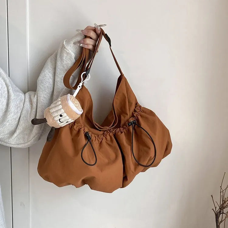 Ultra-light pleated crossbody student cloth bag in soft polyester, showing split pocket and internal phone storage.