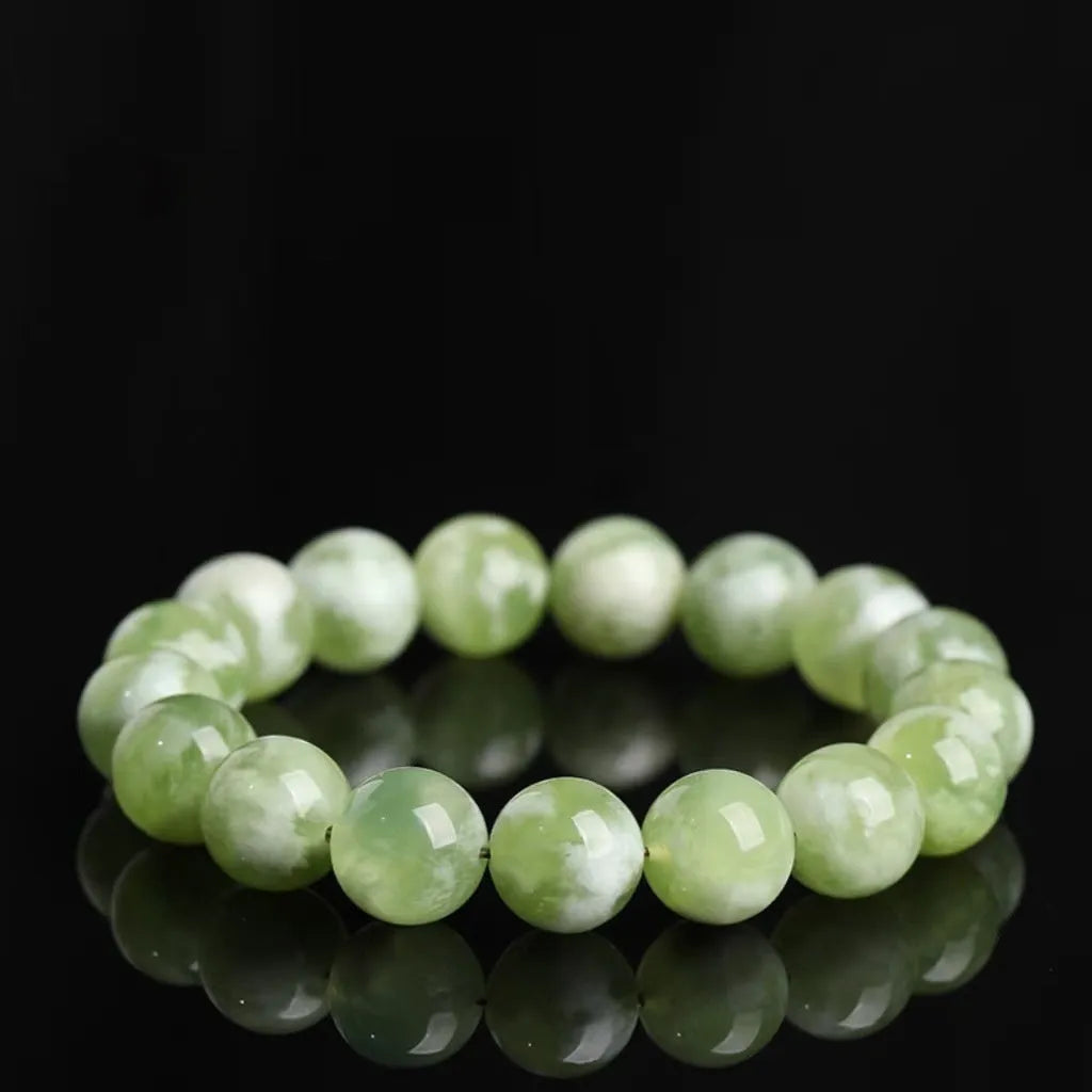 Green milk-in-water Xiuyan jade bracelet with polished geometric beads on white background