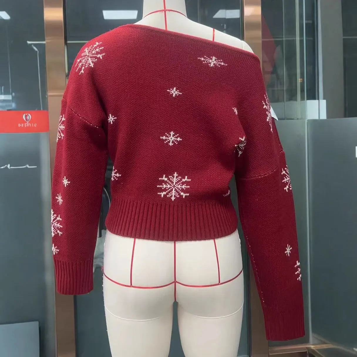 Women's red snowflake jacquard boat neck pullover sweater with long sleeves and crocheted flower details on a white background