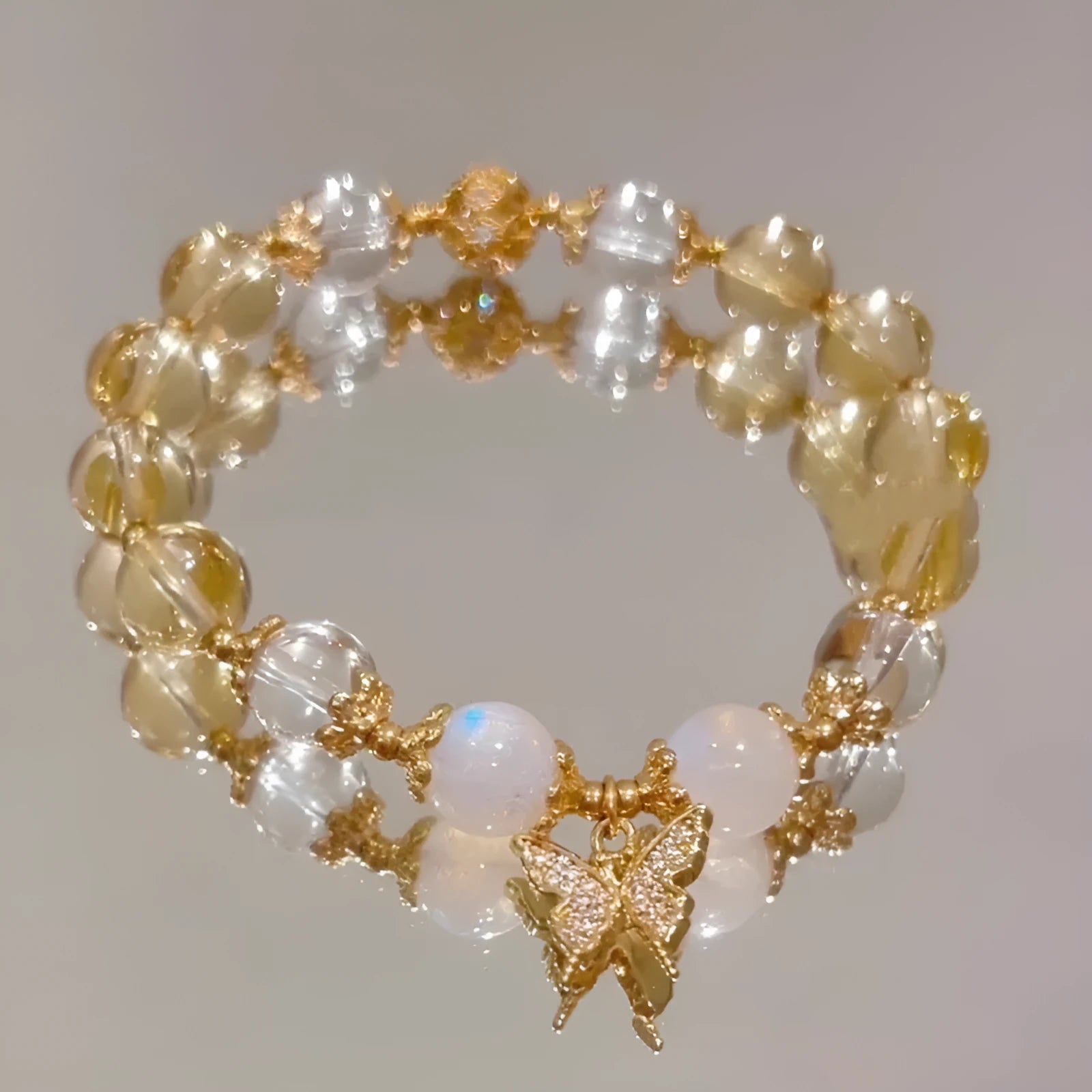Moonstone white crystal beaded bracelet with citrine butterfly charm on display