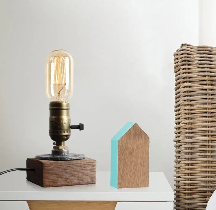 Compact wooden and iron water pipe design table lamp on a table.