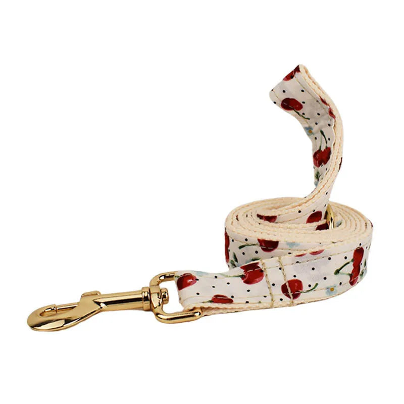 Red cherry printed dog collar set with light gold buckle and bow strap on cloth leash