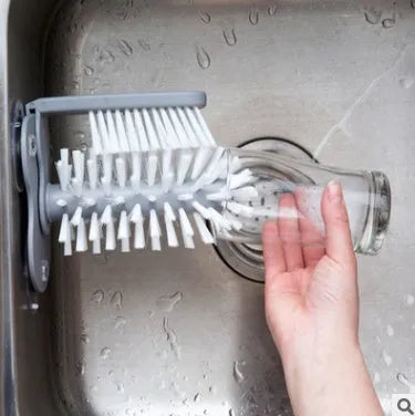 Grey suction cup brush with double-head design and two suction cups on a kitchen wall