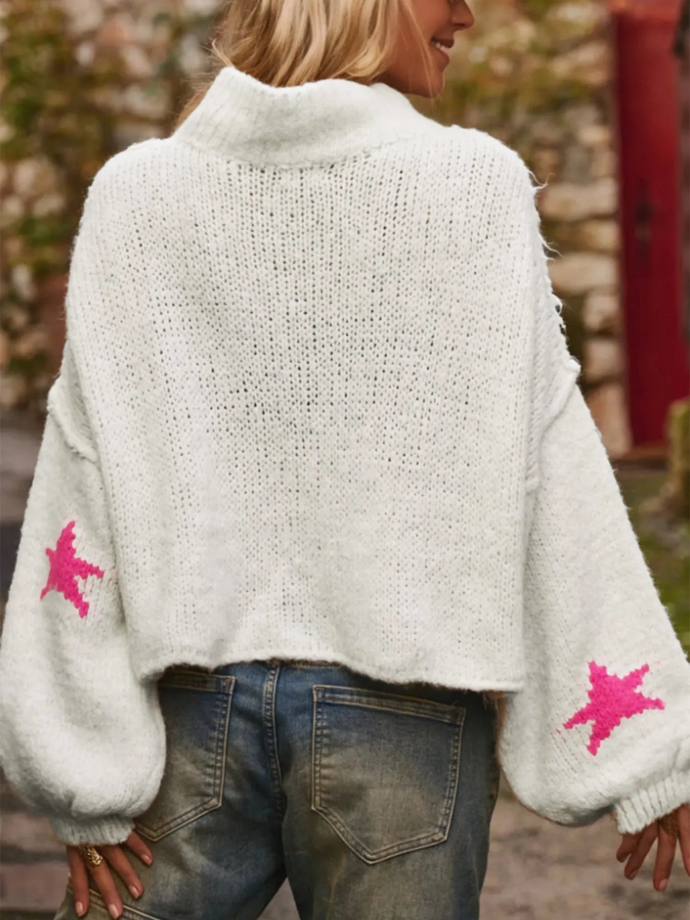 Women's white loose turtleneck pullover sweater with a black five-pointed star pattern on the front.