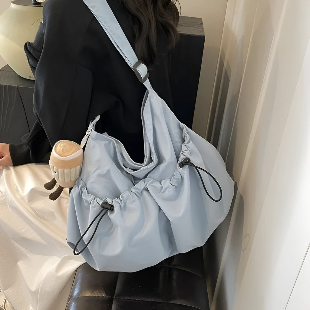 Ultra-light pleated crossbody student cloth bag in soft polyester, showing split pocket and internal phone storage.