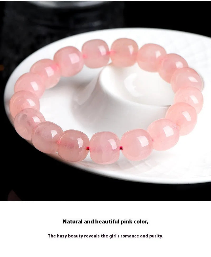 Pink natural crystal barrel bead bracelet with geometric shape on wrist.