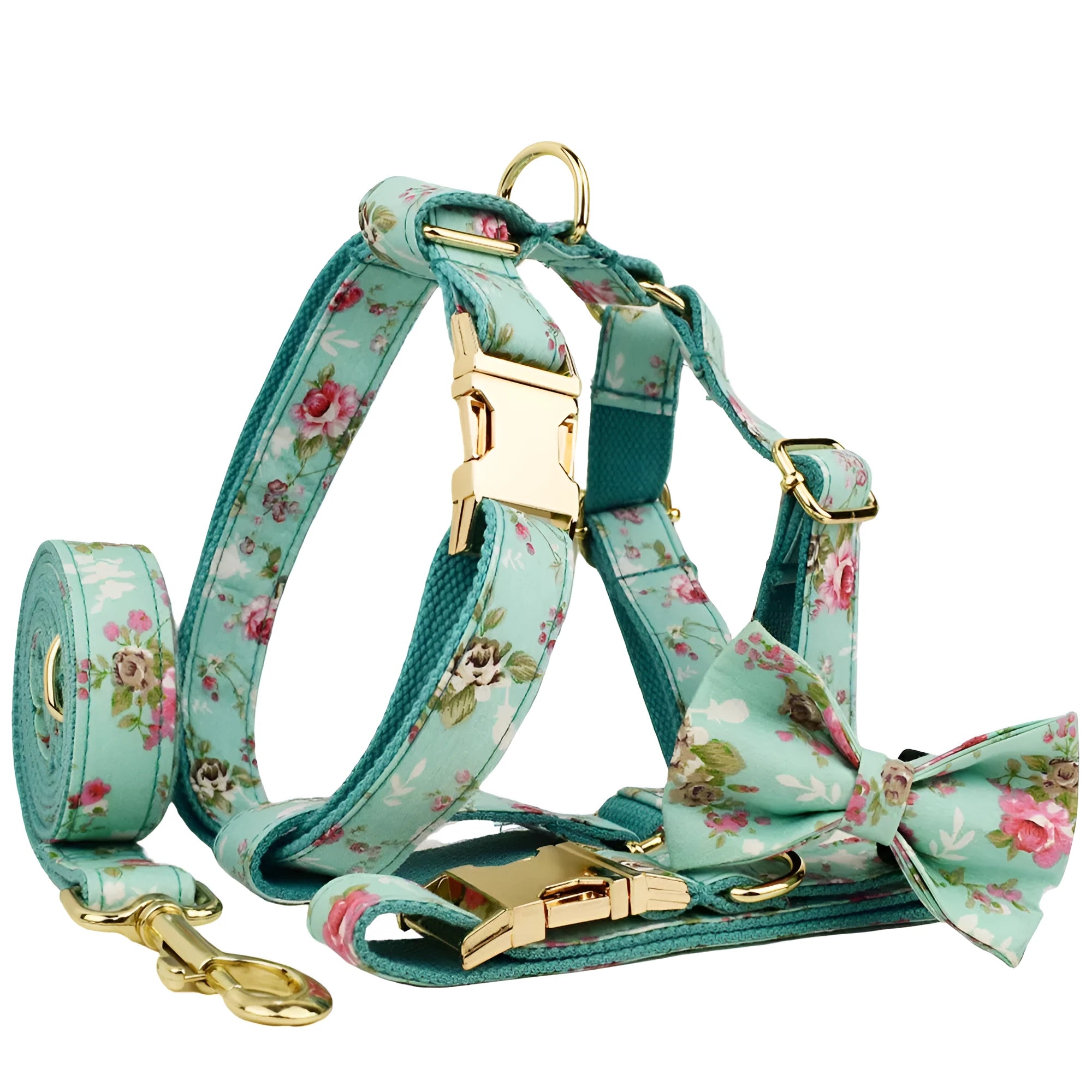 Cloth dog collar with green background and detachable cute bow next to matching leash and vest on a white surface