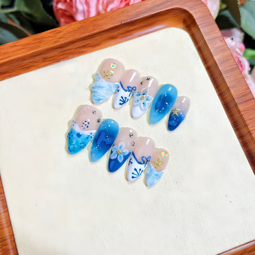 Set of blue transparent false nails with hand-painted carved design, showing sizes XS, S, M, L