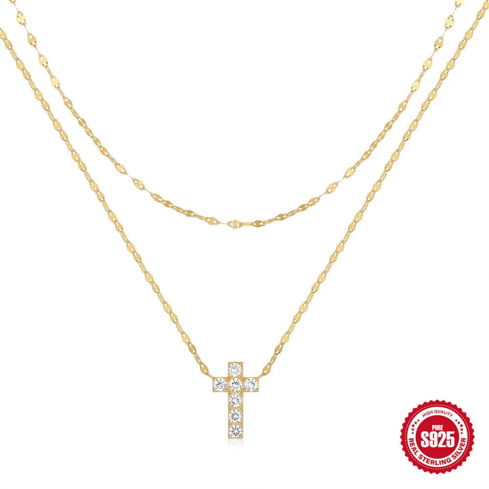 Close-up of a sterling silver double-layer cross pendant necklace with twin diamond accents on a clavicle chain.