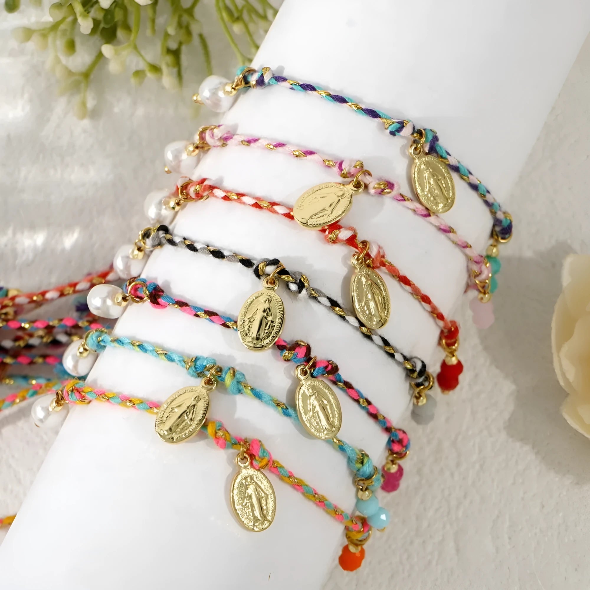 Close-up of a colourful hand-woven braided rope bracelet with a carrying strap tag on a woman's wrist.