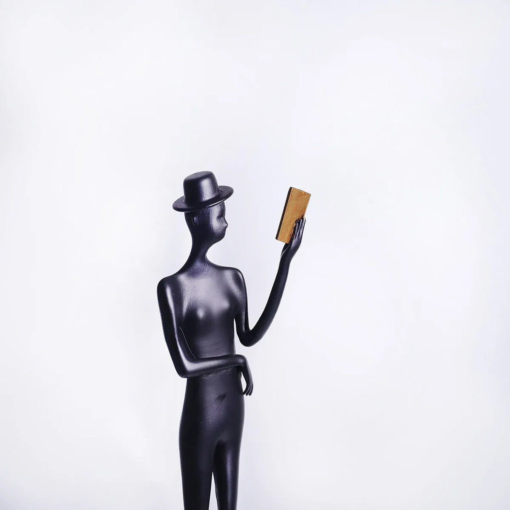 Black cast aluminium reading woman sculpture on desk, modern minimalist design