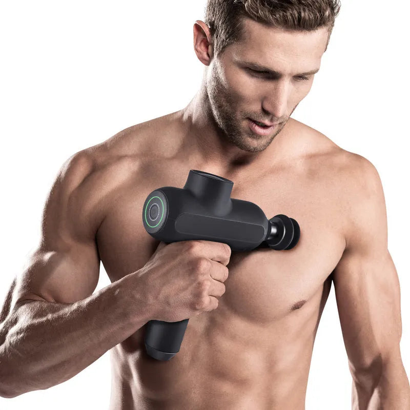 Handheld black muscle percussion massager with six different coloured attachment heads on a table.