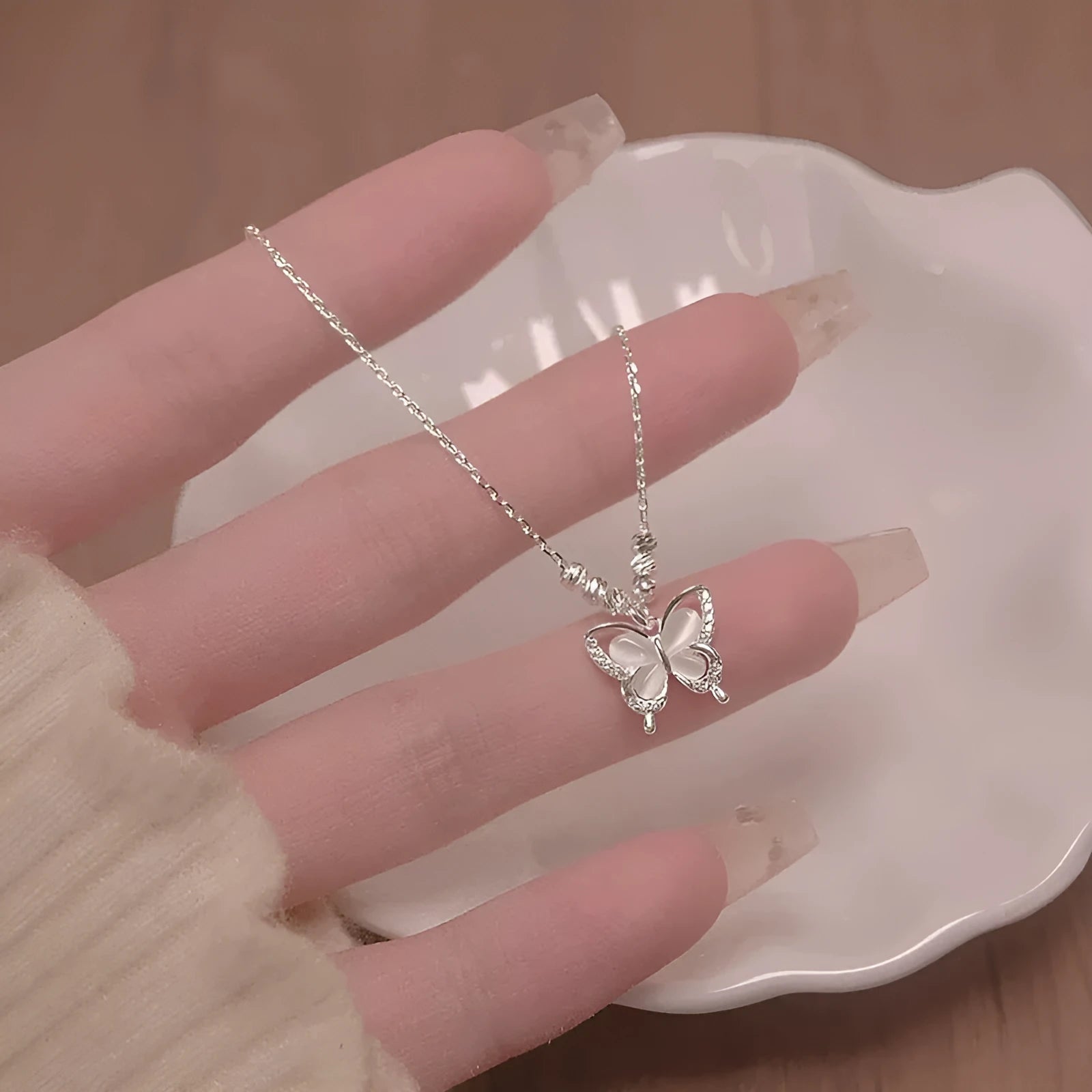Close-up of a women's sterling silver necklace with a square-framed butterfly pendant on an adjustable chain.