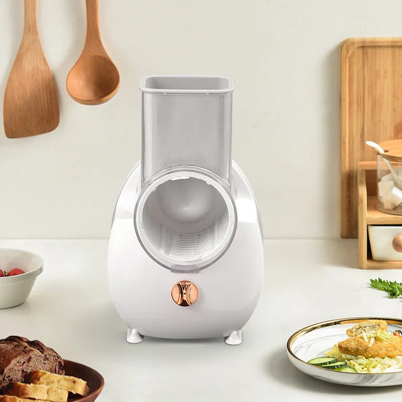 Electric vegetable slicer in white with feeding port, pressing rod, and blade barrel on a kitchen counter