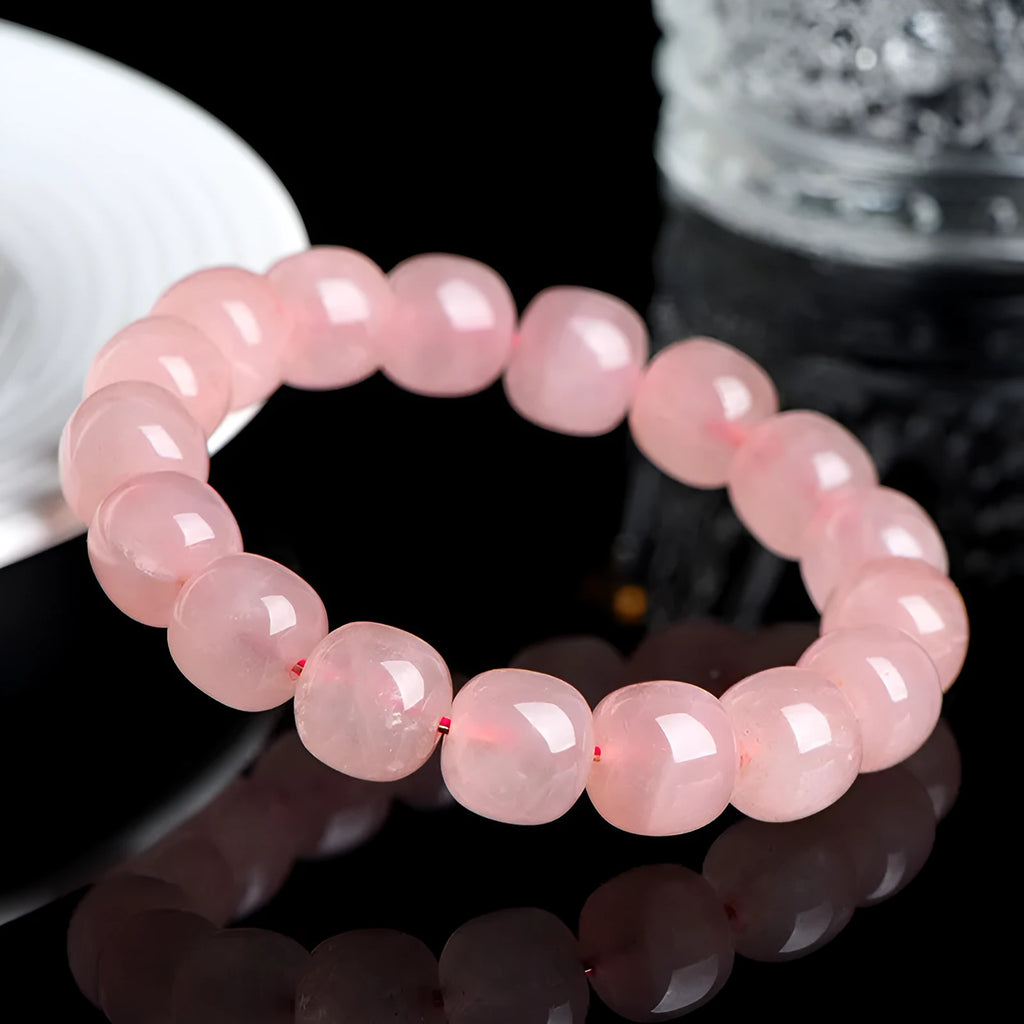 Pink natural crystal barrel bead bracelet with geometric shape on wrist.