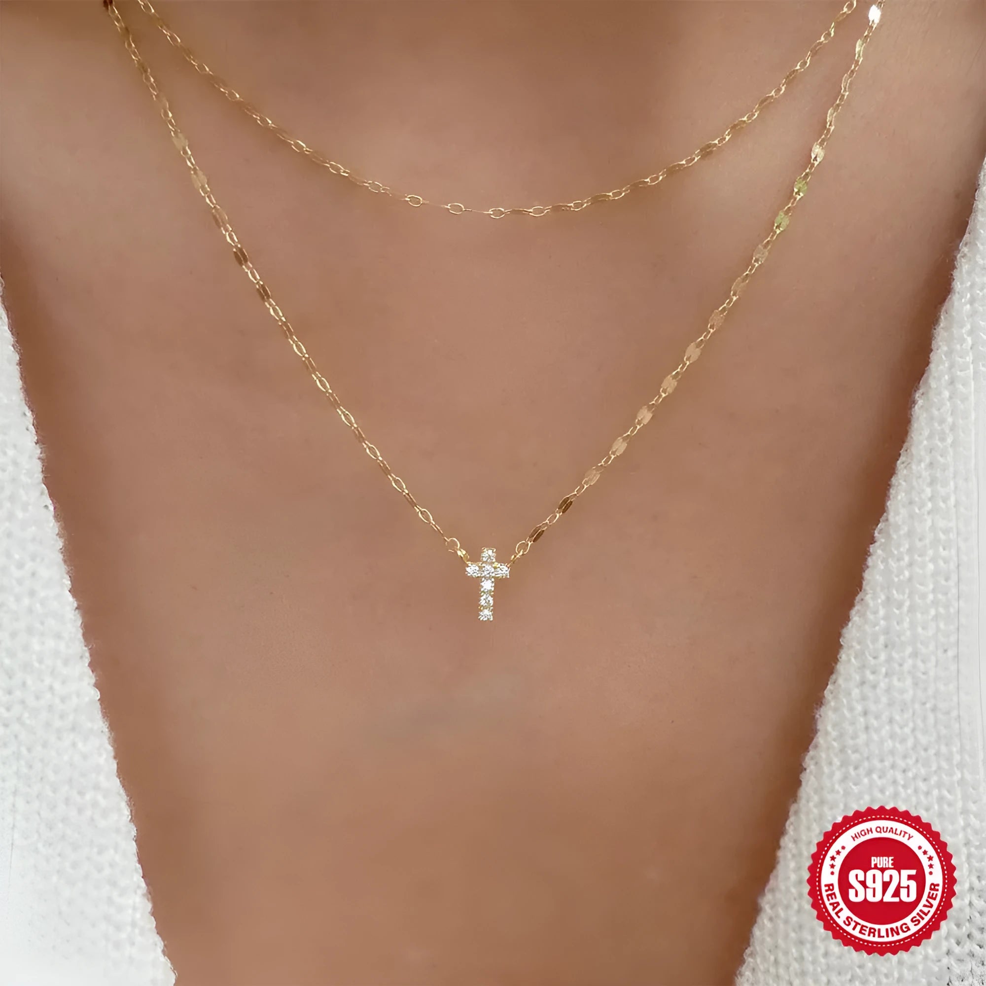 Close-up of a sterling silver double-layer cross pendant necklace with twin diamond accents on a clavicle chain.