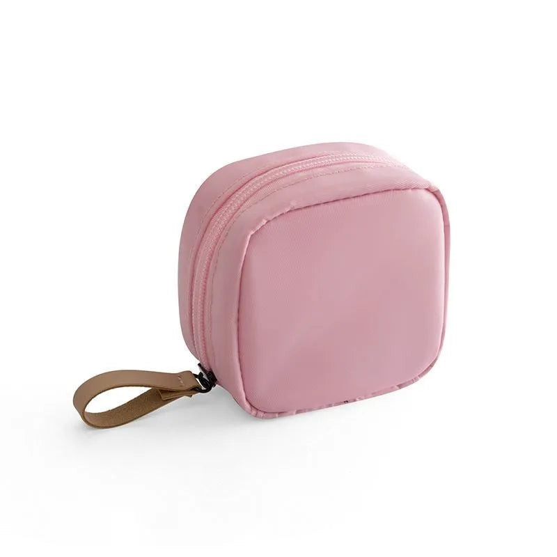 A blue cloth cube-shaped makeup storage bag sitting upright, showing its plain fabric design.