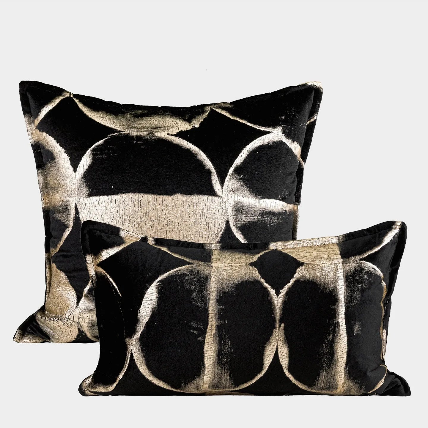 Black and gold abstract patterned decorative flannel cushion on a grey sofa.