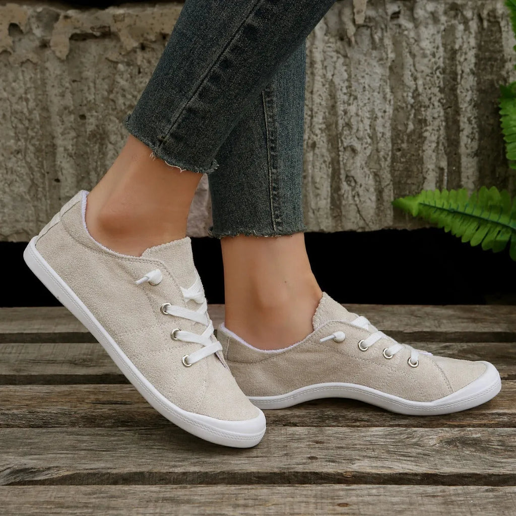 Women's creamy white fabric casual sneakers with rubber soles showing low-top design
