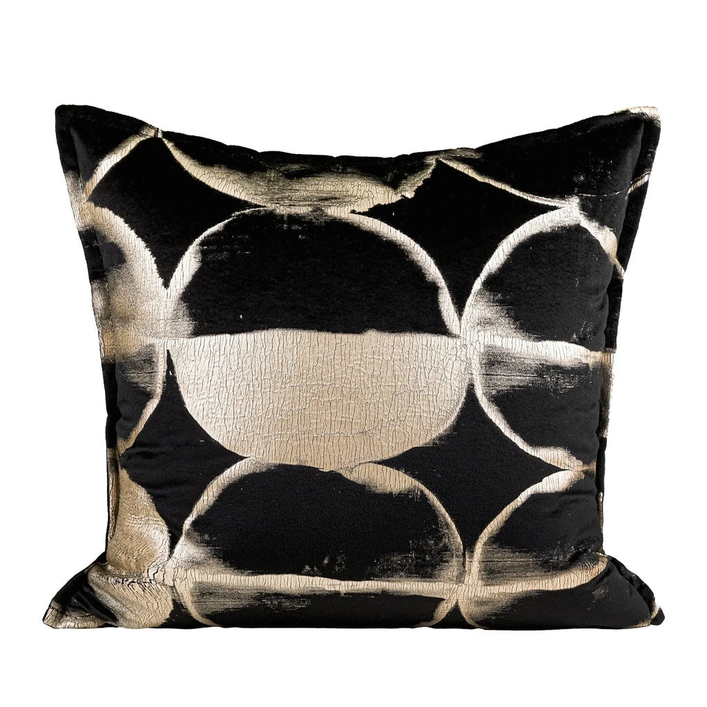 Black and gold abstract patterned decorative flannel cushion on a grey sofa.