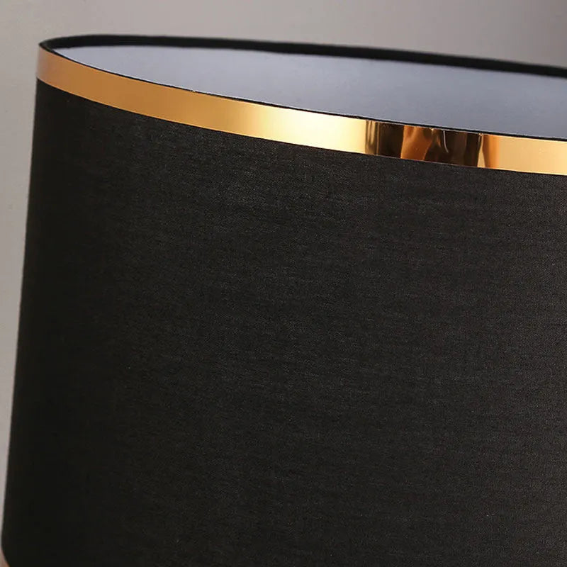 Simple bedroom table lamp with black iron body and cloth lampshade on a desk