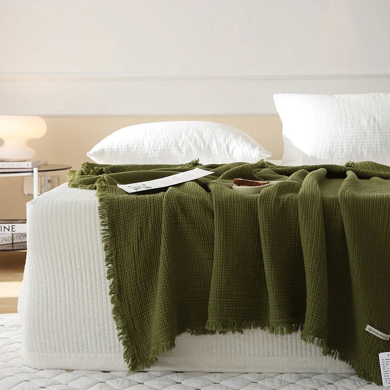 Four-layer gauze tassel cotton blanket in avocado green colour laid flat.