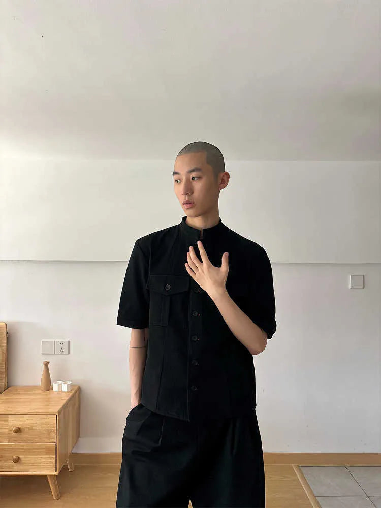 Handmade black loose fit half sleeve hunting shirt with a shirt collar, laid flat.