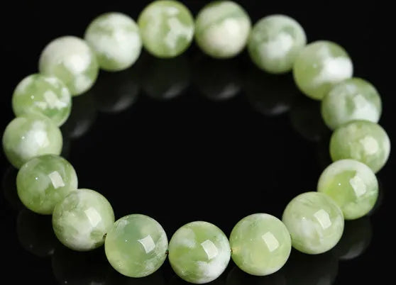 Green milk-in-water Xiuyan jade bracelet with polished geometric beads on white background
