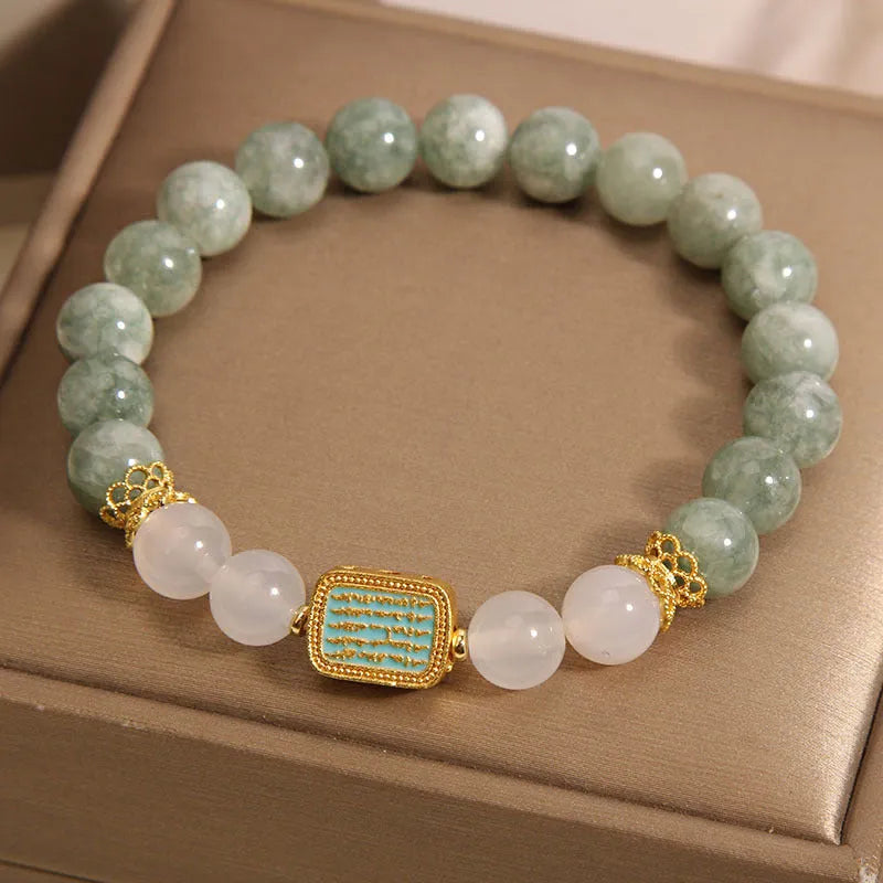 Women's oil green emerald crystal bracelet with five scripture pieces on a wrist.
