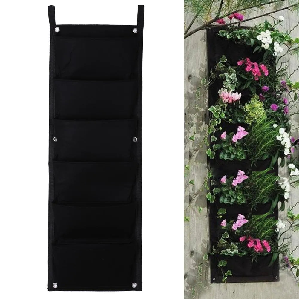 Green felt vertical wall planter with multiple planting pockets hanging on an outdoor wall.