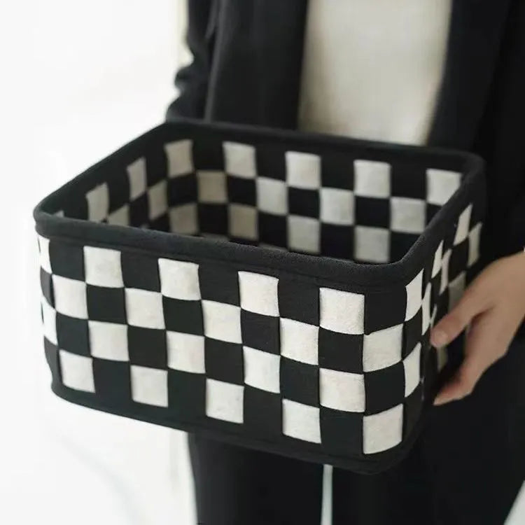 Black and white checkerboard woven felt storage basket with folded sides.