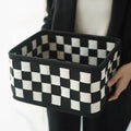 Black and white checkerboard woven felt storage basket with folded sides.