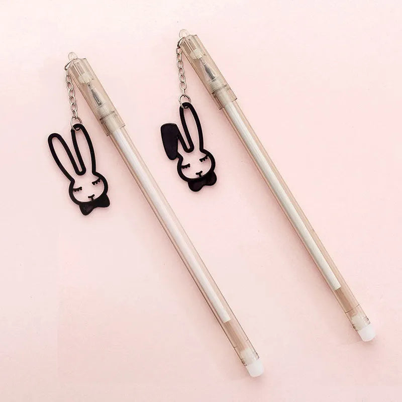 White gel pen with paper crane pendant and black gel pen with rabbit pendant on cap.