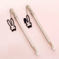 White gel pen with paper crane pendant and black gel pen with rabbit pendant on cap.