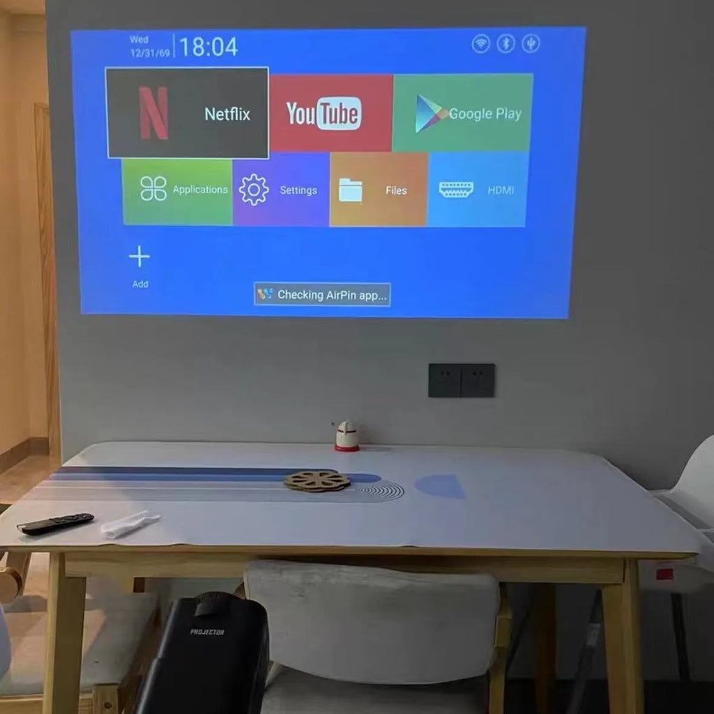 A wireless home projector with a carrying handle, displaying a bright game or movie on a wall.
