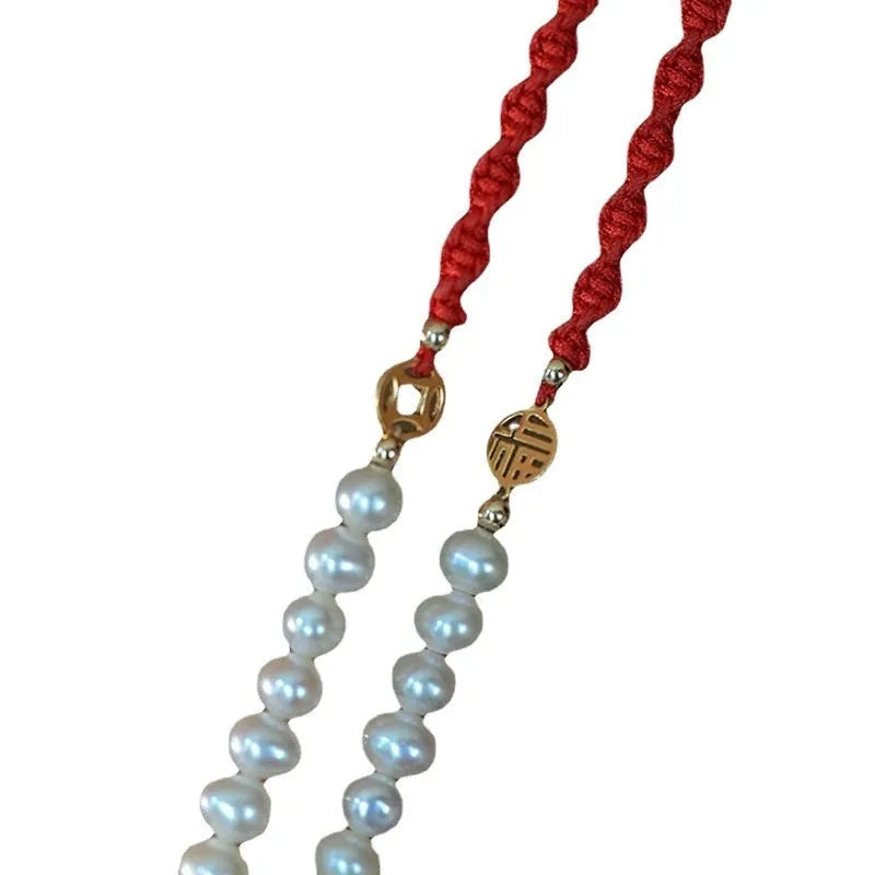 Women's pearl braided red rope bracelet with 14K gold plated fu character charm in geometric shape on white background