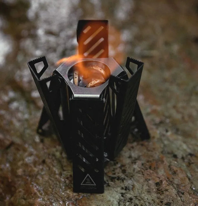 Hexagon-shaped foldable alcohol stove for camping in black or silver with 9.5x8.5x15cm dimensions
