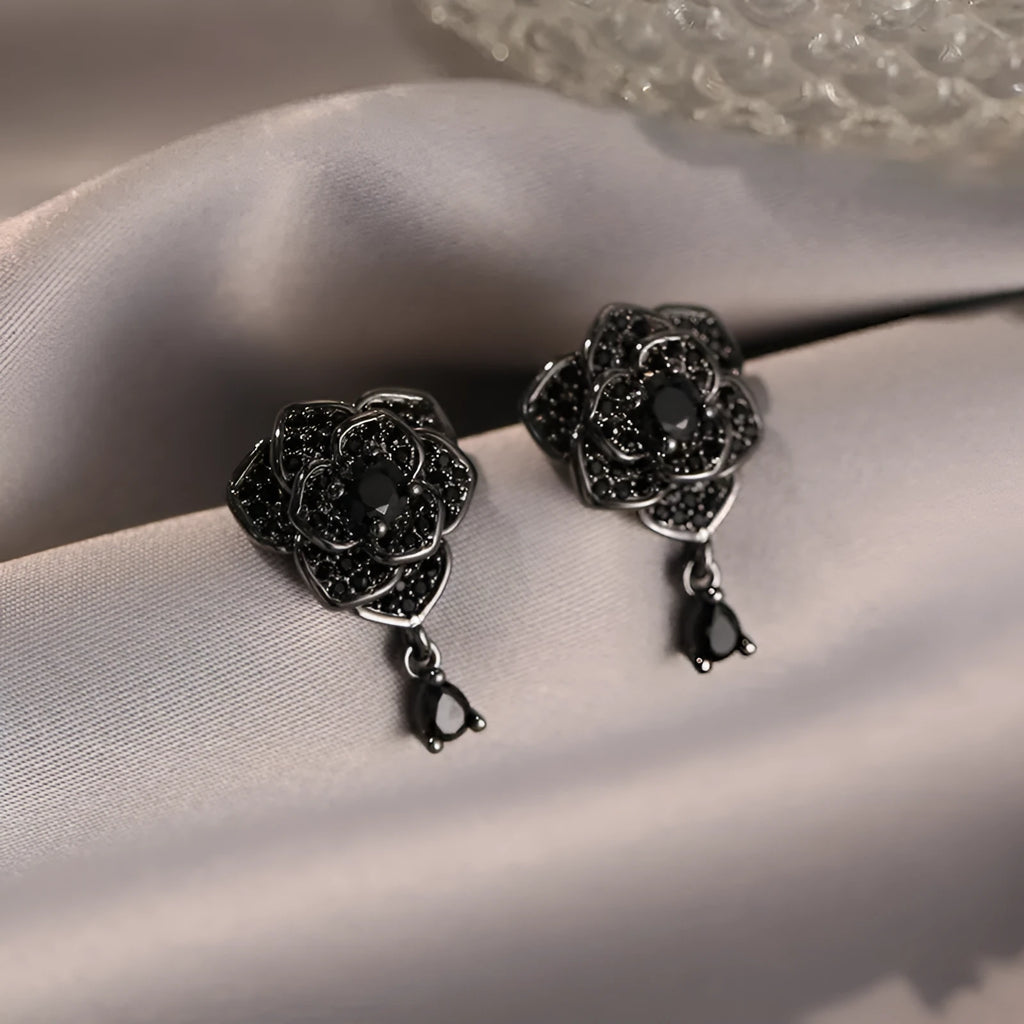 Black rose zircon inlaid stud earrings with 18K gold plated copper flower shape on white background